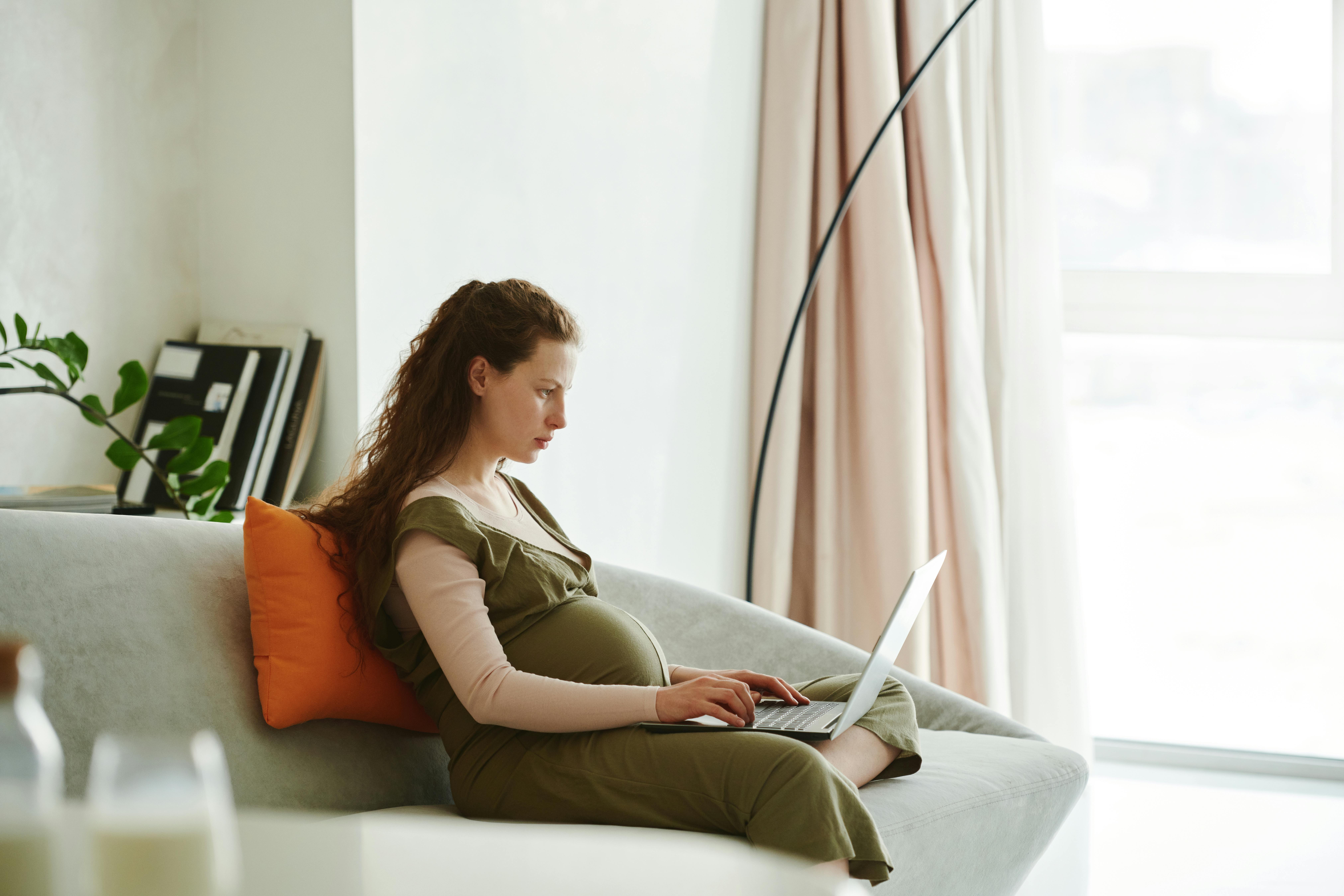 Pregnant woman on couch with laptop
